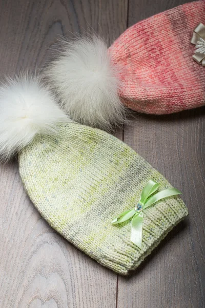 Růžové a zelené pletené čepice na dřevěné desce — Stock fotografie