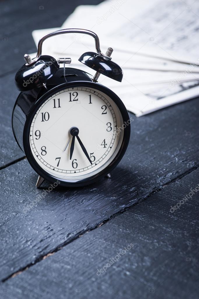 Alarm clock with newspaper on a wooden table