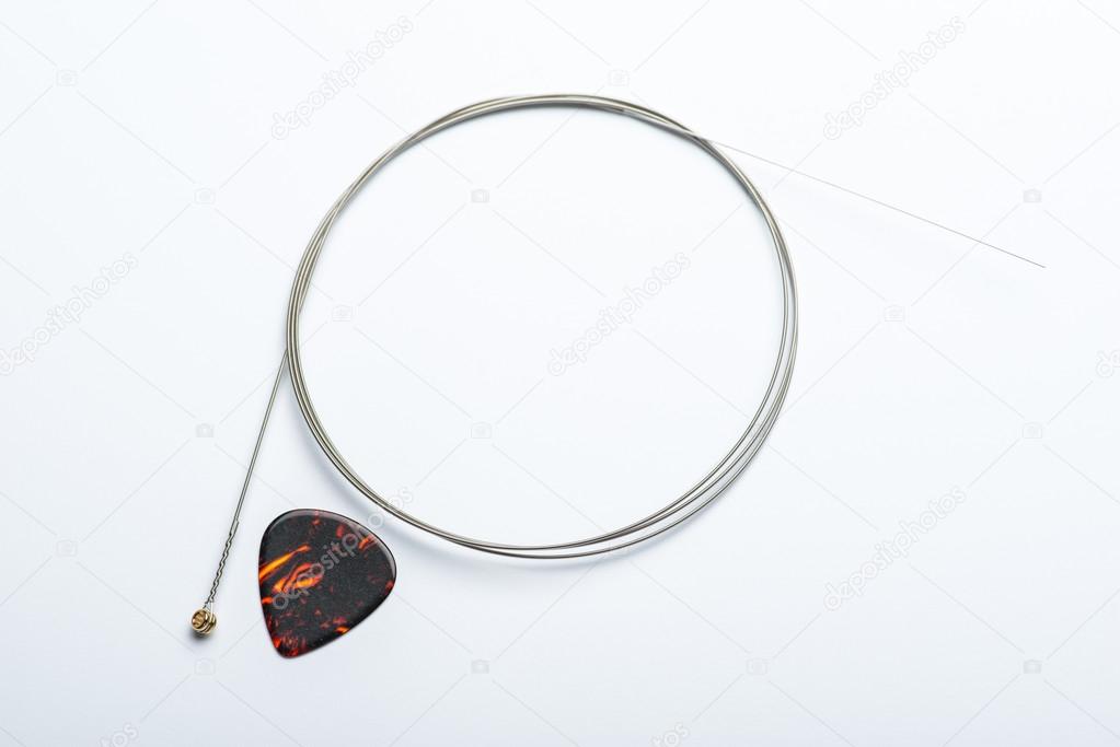 Electric guitar string with mediator on white surface