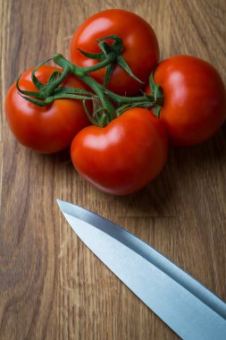 Ahşap bir masa üzerinde bıçak ile taze ve lezzetli domates