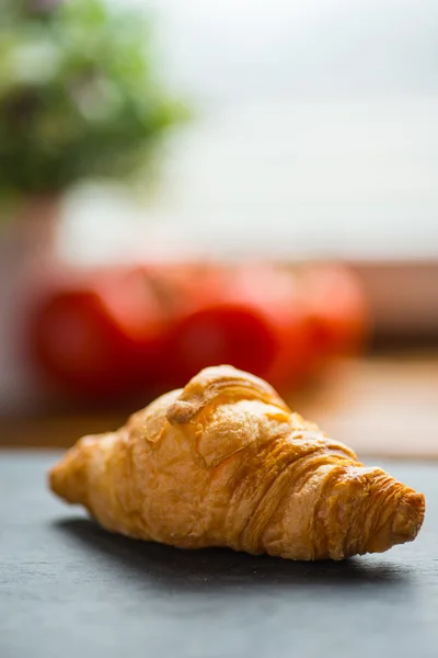 Croissant saboroso francês em uma mesa de madeira perto da janela — Fotografia de Stock