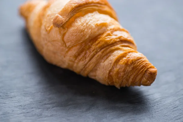 Chutné francouzským croissantem na černou kamennou desku — Stock fotografie