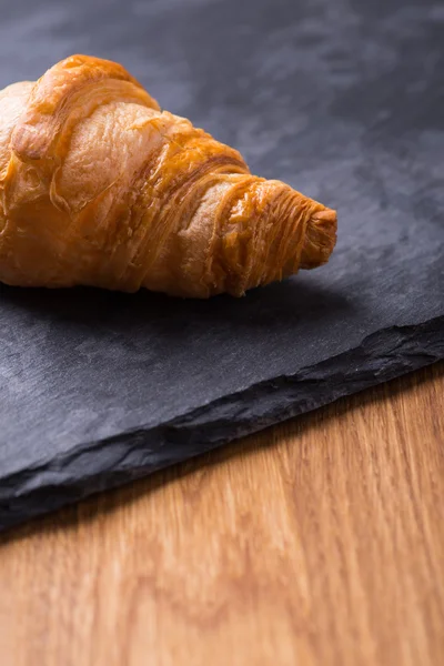 Chutné francouzským croissantem na černou kamennou desku — Stock fotografie