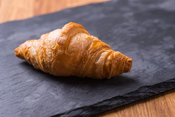 Chutné francouzským croissantem na černou kamennou desku — Stock fotografie