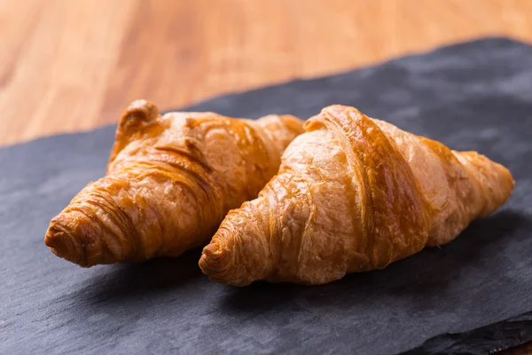 Chutné francouzským croissantem na černou kamennou desku — Stock fotografie