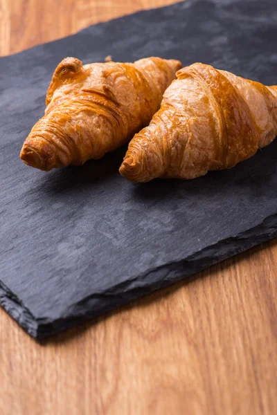 Chutné francouzským croissantem na černou kamennou desku — Stock fotografie