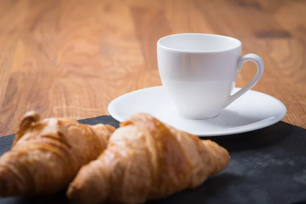 Dvě chutné francouzské croissanty s šálkem kávy — Stock fotografie