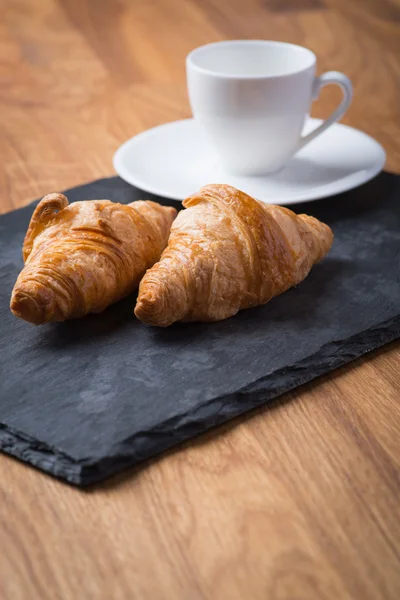Dvě chutné francouzské croissanty s šálkem kávy — Stock fotografie