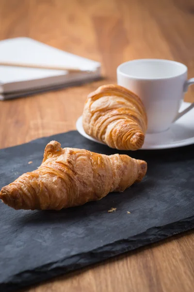 Dvě chutné francouzské croissanty s šálkem kávy a notebook — Stock fotografie