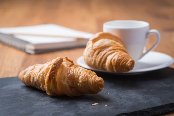 Dvě chutné francouzské croissanty s šálkem kávy a notebook — Stock fotografie