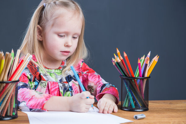 Маленькая девочка рисует картинки с карандашами
