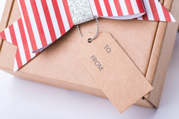 Caja de regalo de cartón marrón con un lazo rojo y etiqueta — Foto de Stock