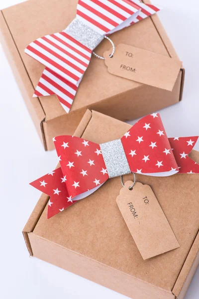Brown cardboard gift box with a red bow and tag — Stock Photo, Image