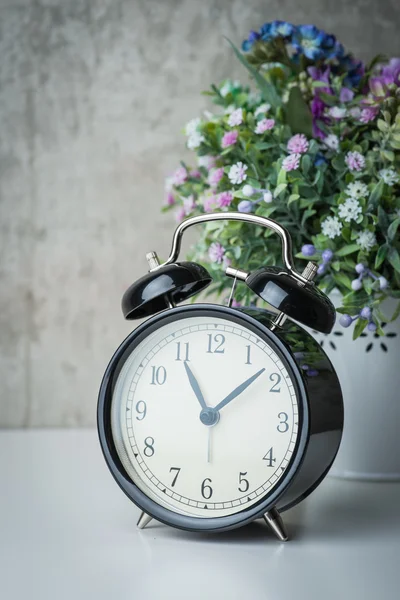 Althergebrachter Wecker auf weißem Tisch mit Blumen — Stockfoto