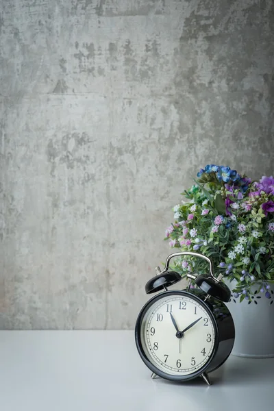 Althergebrachter Wecker auf weißem Tisch mit Blumen — Stockfoto
