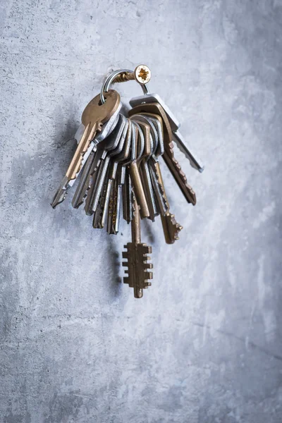 Купка старих зношених ключів на сірій бетонній стіні — стокове фото