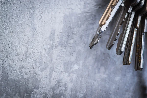 A bunch of old worn keys on the grey concrete wall — Stock Photo, Image