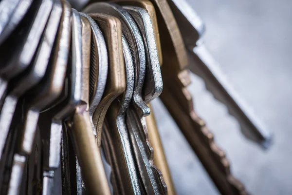 A bunch of old worn keys on the grey concrete wall — Stock Photo, Image