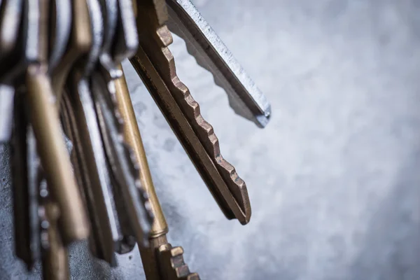 Un montón de viejas llaves desgastadas en la pared de hormigón gris —  Fotos de Stock