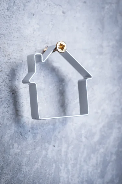 Metal house hanging on the screw in the grey concrete wall — Stock Photo, Image