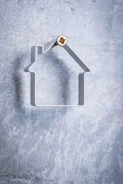 Metal house hanging on the screw in the grey concrete wall — Stock Photo, Image