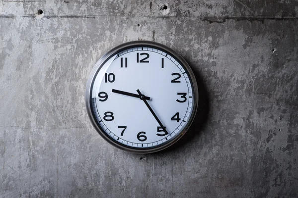 Relógio de parede redonda pendurado na parede de concreto cinza — Fotografia de Stock