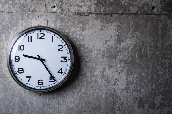 Round wall clock hanging on the grey concrete wall — Stock Photo, Image