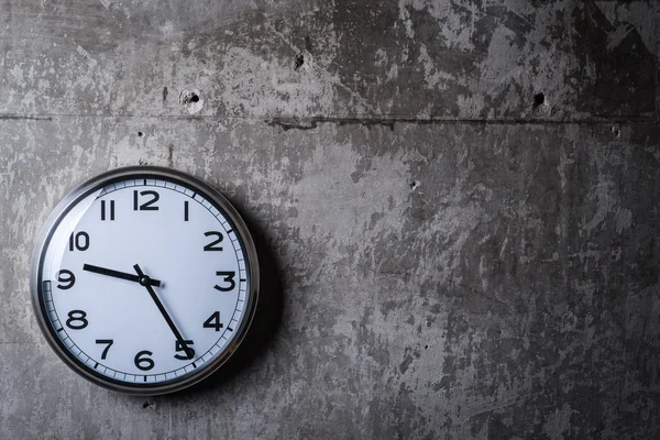 Kulaté nástěnné hodiny visí na šedou betonovou zeď — Stock fotografie