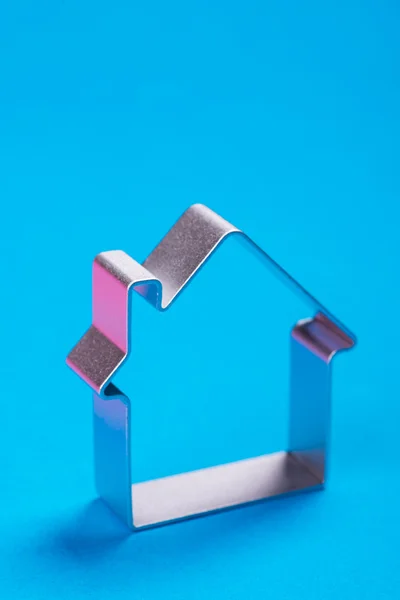 Metal house standing on a blue surface — Stock Photo, Image