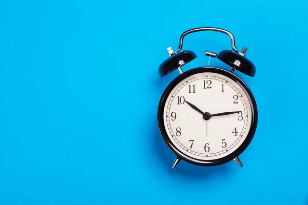 Old vintage alarm clock standing on the blue surface — Stock Photo, Image