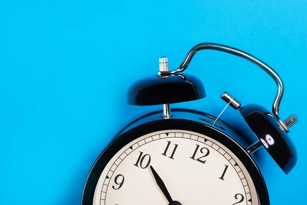 Old vintage alarm clock standing on the blue surface — Stock Photo, Image