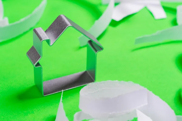Kovové dům, stojící na zeleném povrchu s teared papírky Royalty Free Stock Obrázky