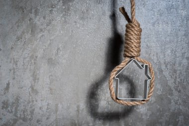 Küçük ev gri beton duvardan Hangman's noose ile çerçeveli