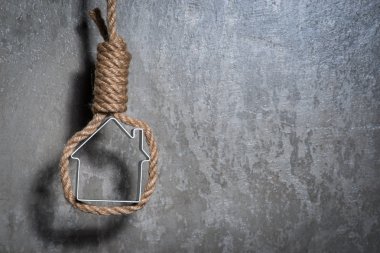 Küçük ev gri beton duvardan Hangman's noose ile çerçeveli