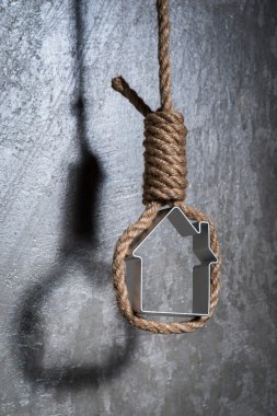 Küçük ev gri beton duvardan Hangman's noose ile çerçeveli