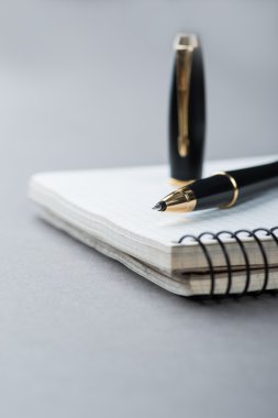 Gri arka plan üzerinde siyah topu kalemiyle bir spiral defter