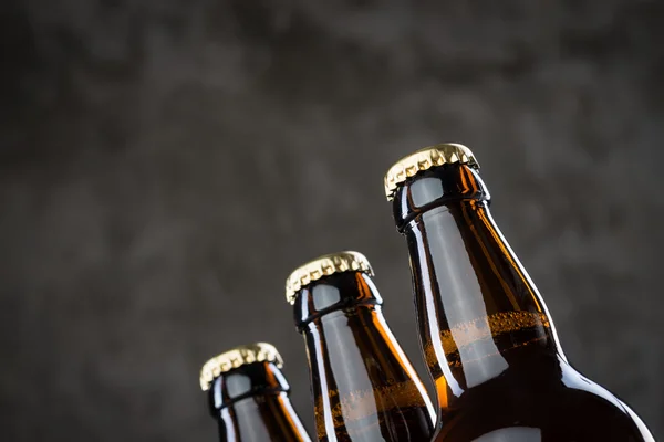 Bottiglie di birra appena preparate in fila sopra il muro di cemento grigio — Foto Stock