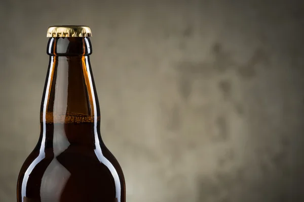 Bouteilles de bière fraîchement brassées en rangée sur le mur de béton gris — Photo