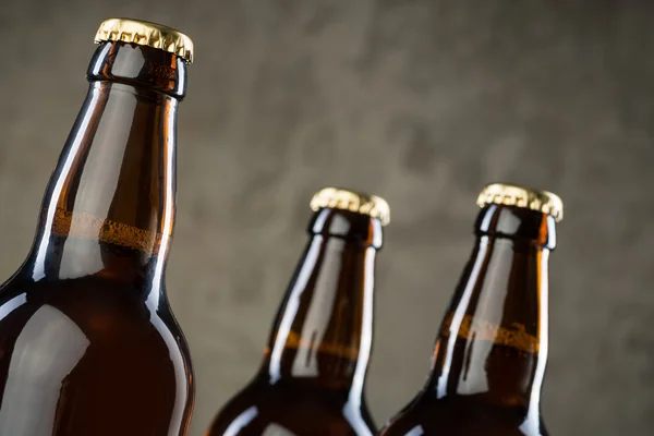 Bouteilles de bière fraîchement brassées en rangée sur le mur de béton gris — Photo