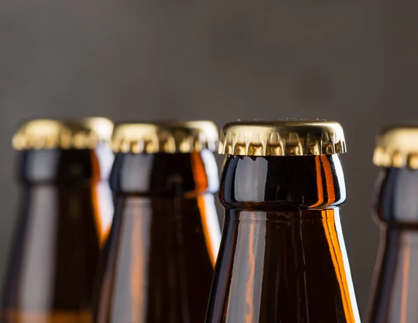 Bottiglie di birra appena preparate in fila sopra il muro di cemento grigio — Foto Stock