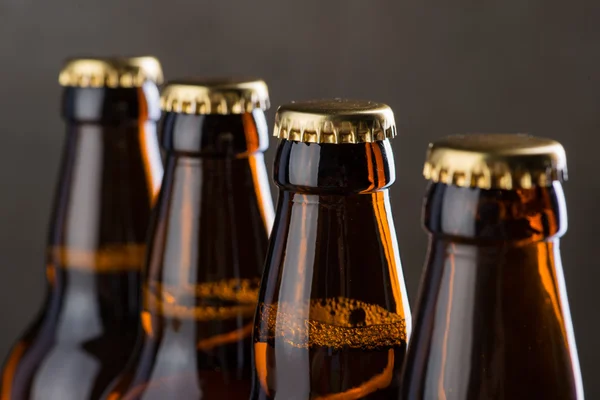 Bouteilles de bière fraîchement brassées en rangée sur le mur de béton gris — Photo