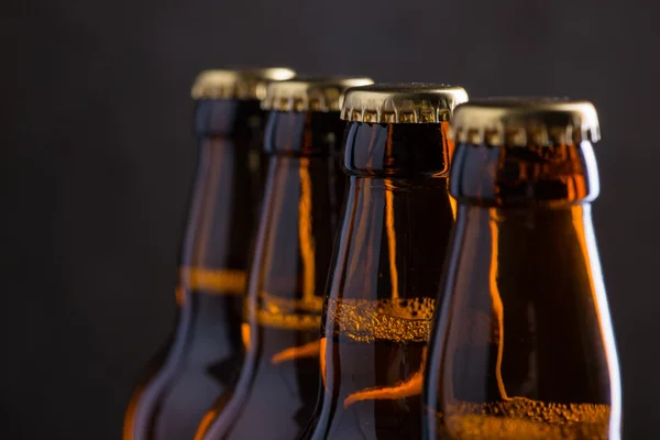 Garrafas de cerveja recém-fabricadas em uma fileira sobre a parede de concreto cinza — Fotografia de Stock