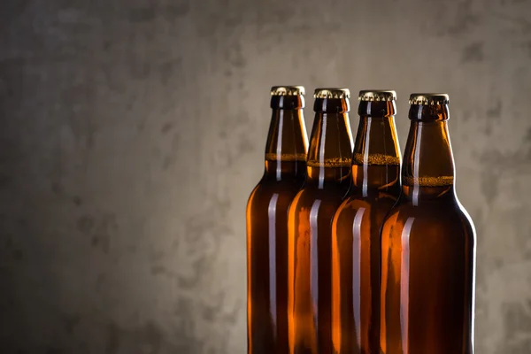 Свіжозварені пляшки пива поспіль над сірою бетонною стіною — стокове фото