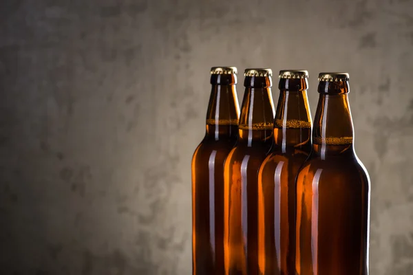 Bottiglie di birra appena preparate in fila sopra il muro di cemento grigio — Foto Stock