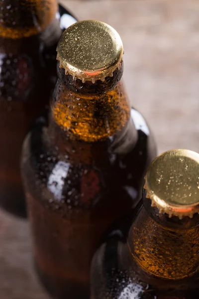 Bouteilles de bière fraîchement brassées en rangée sur le mur de béton gris — Photo