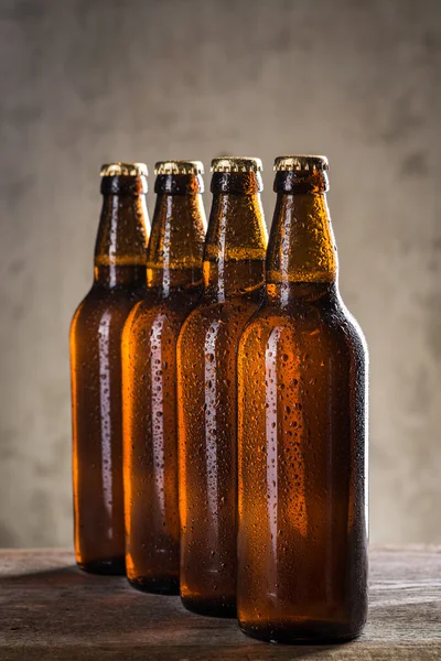 Bouteilles de bière fraîchement brassées en rangée sur le mur de béton gris — Photo