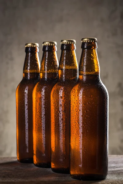 Φρεσκοκομμένο μπουκάλια μπύρας σε μια σειρά πάνω από τον γκρίζο σκυρόδεμα τοίχο — Φωτογραφία Αρχείου
