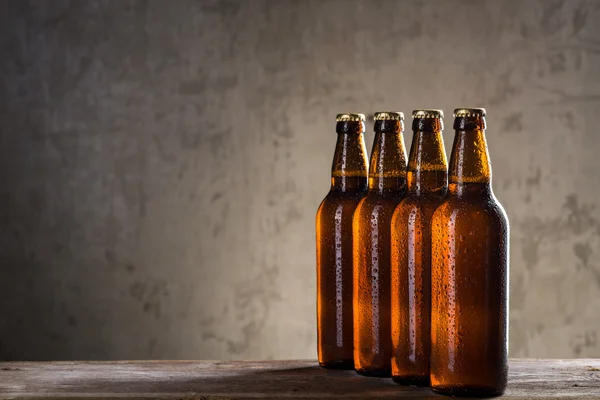 Garrafas de cerveja recém-fabricadas em uma fileira sobre a parede de concreto cinza — Fotografia de Stock