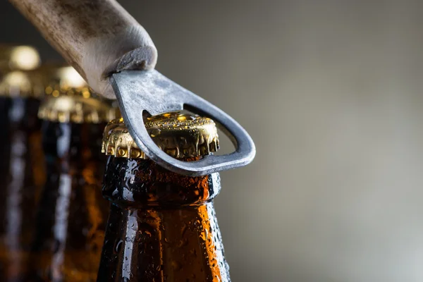 Коричневі пляшки холодного пива з старим відкривачем — стокове фото