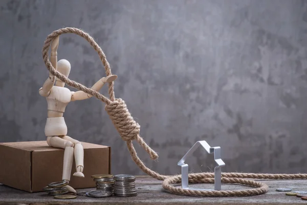 Petit mannequin en bois assis avec corde du bourreau, maison et pièces de monnaie — Photo